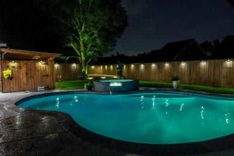 A backyard swimming pool and Hot Tub hot tob at night